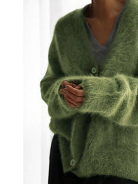 Green cardigan worn by a person on a white background