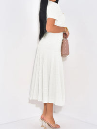Person wearing a white pleated skirt and high-heeled shoes on a white background