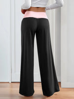 Person wearing black wide-leg pants with a white top and pink waistband.