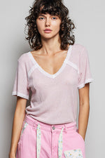 Woman wearing a light pink textured top and pink pants against a plain background
