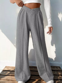 Gray sweatpants worn by a person on a wooden platform with a light background
