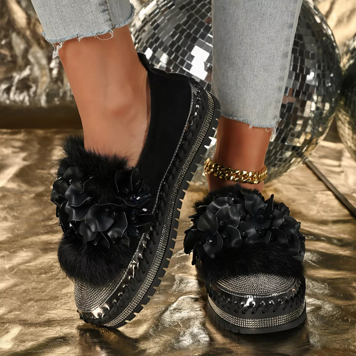 Black floral embellished shoes on a reflective surface