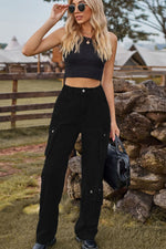 Woman in black outfit standing outdoors near a stone wall