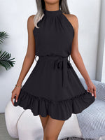 Black sleeveless dress with ruffled hem worn by a person indoors.