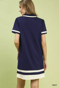 Woman wearing a navy dress with white trim on a light green background