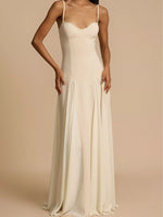 Woman wearing a long, light-colored dress against a beige background