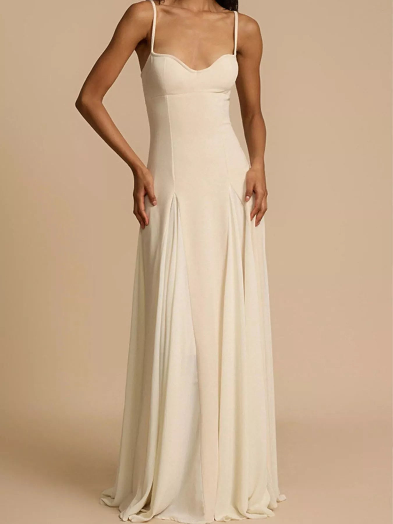 Woman wearing a long, light-colored dress against a beige background