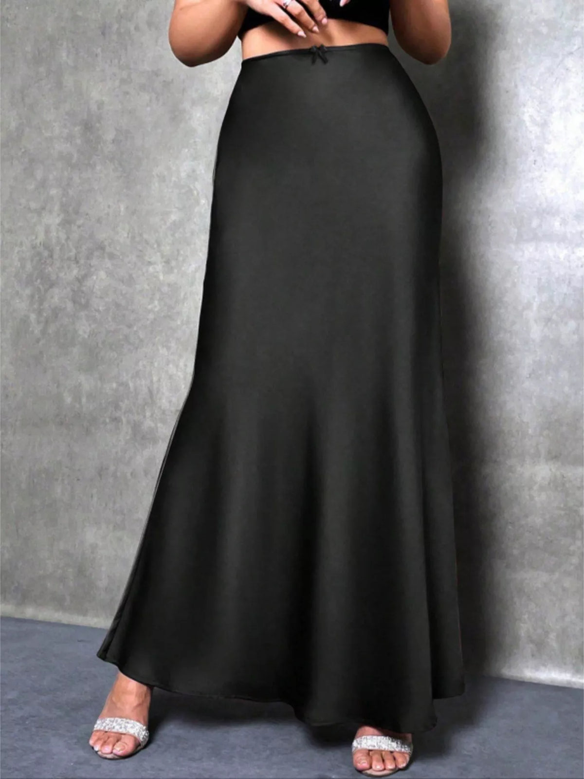 Person wearing a long black skirt against a gray background