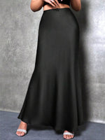 Person wearing a long black skirt against a gray background