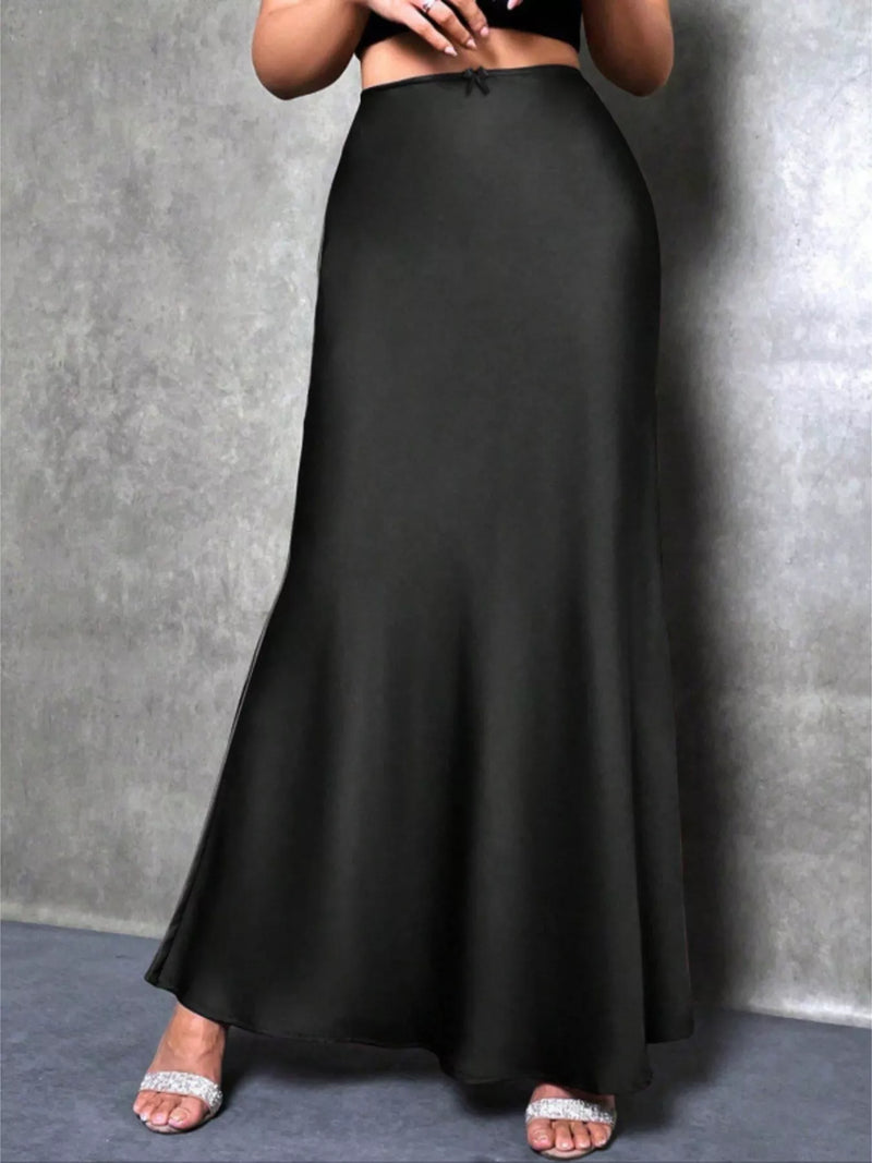 Person wearing a long black skirt against a gray background