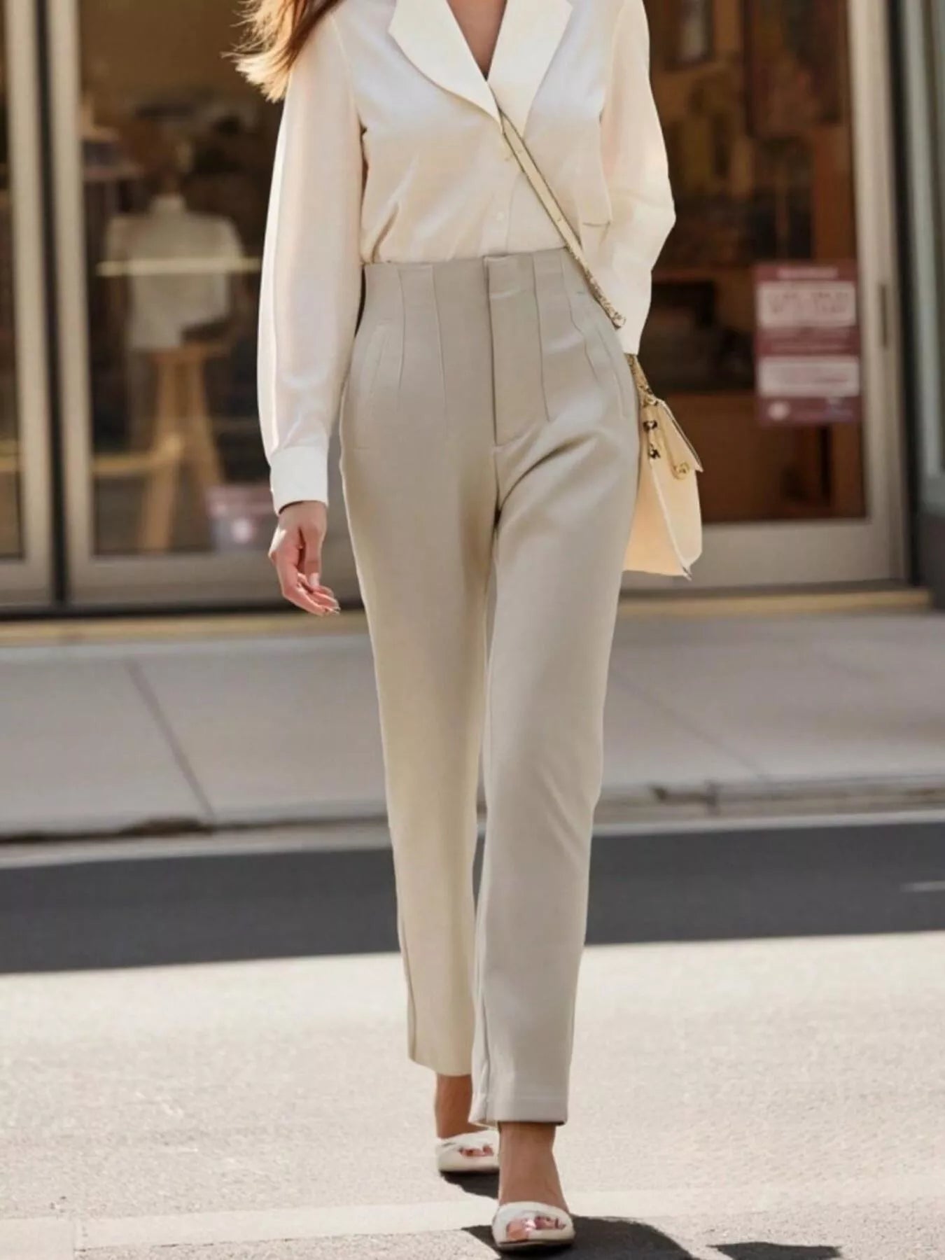 Person wearing a beige suit walking on a city street.