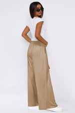 Woman wearing a white top and beige wide-leg pants on a white background