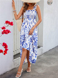 Woman wearing a blue and white patterned dress standing against a white wall with red flowers.