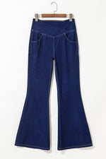 Blue denim bell-bottom pants on a hanger against a white background