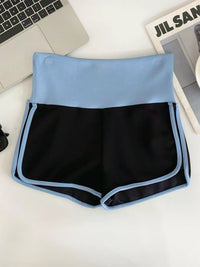 Black and blue shorts on a white surface with a laptop and magazine in the background.