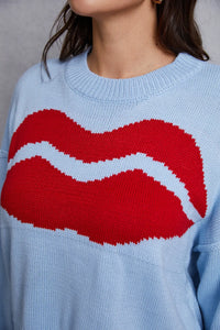 Light blue sweater with a large red and white graphic on a neutral background