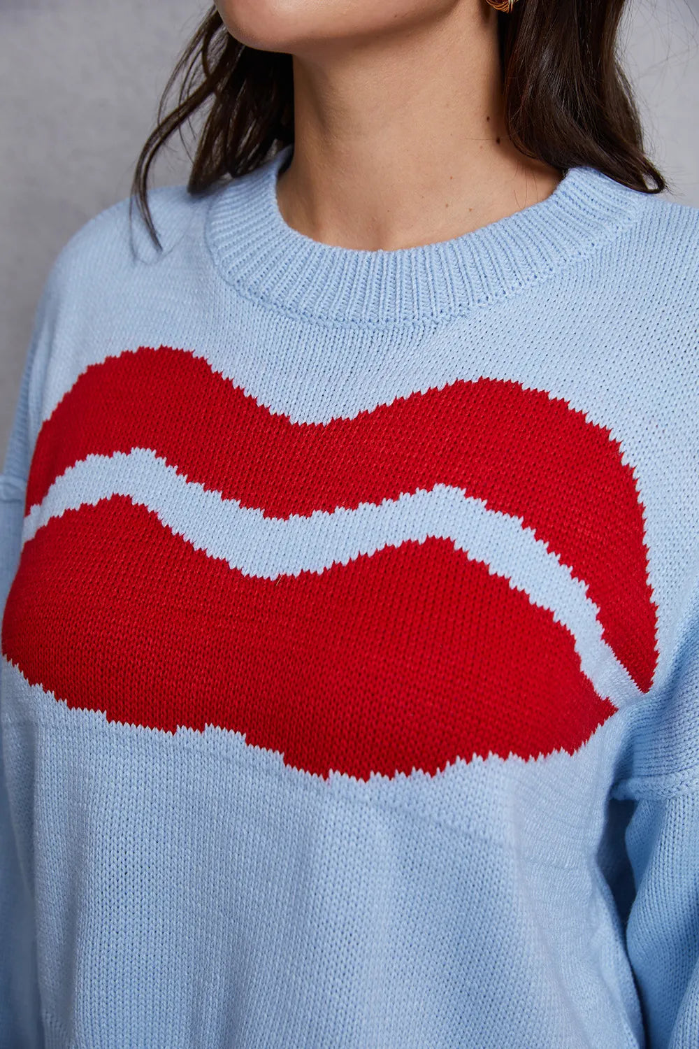 Light blue sweater with a large red and white graphic on a neutral background