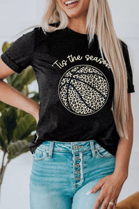 Person wearing a black t-shirt with 'Tis the season' text and snowflake design, standing outdoors.