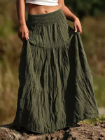 Person wearing a long green skirt with a blurred natural background
