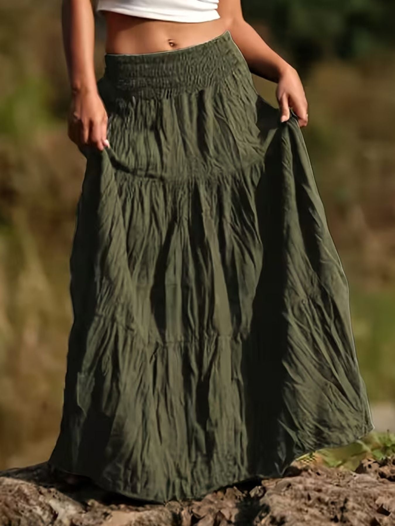 Person wearing a long green skirt with a blurred natural background