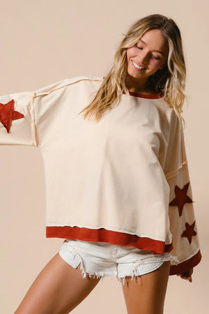 Woman wearing a cream sweater with red star patterns and denim shorts on a beige background