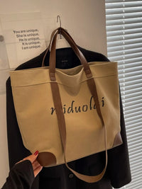 Beige tote bag with brown handles hanging on a hook against a white wall.