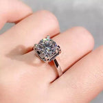 Silver ring with a large gemstone on a hand against a neutral background
