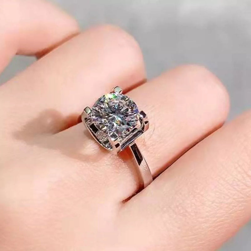 Silver ring with a large gemstone on a hand against a neutral background