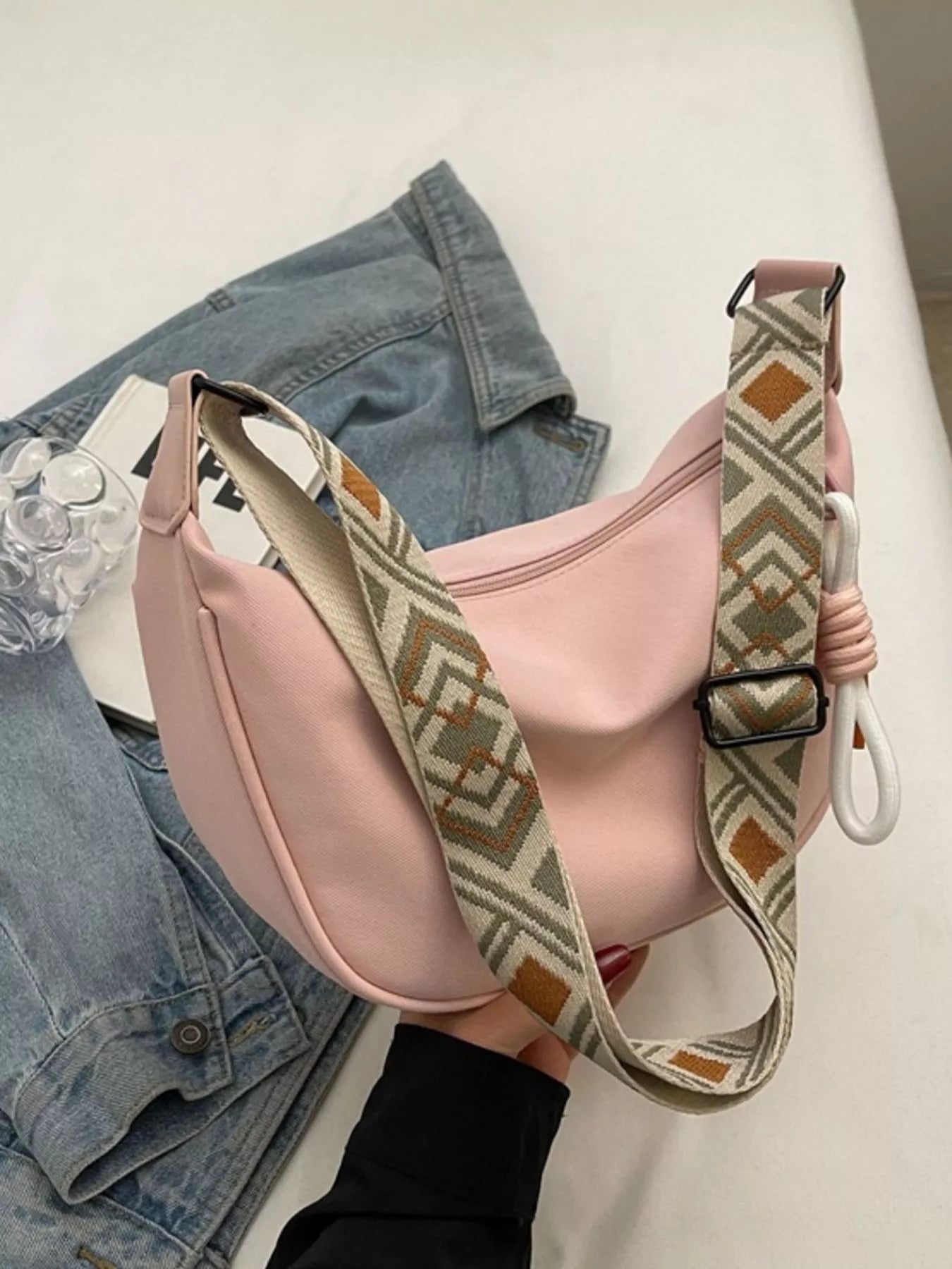 Pink bag with a patterned strap on a white surface
