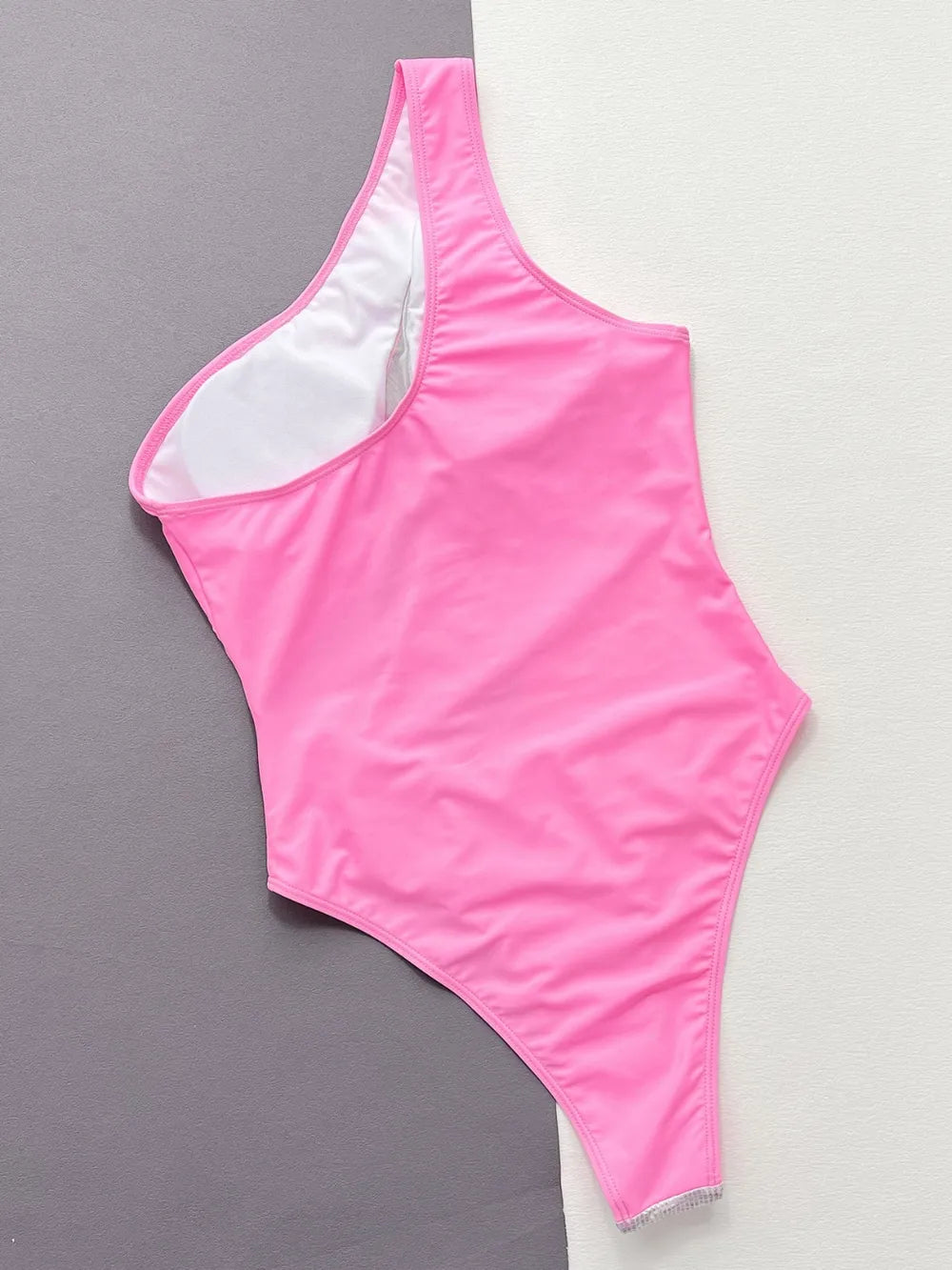 Pink one-piece swimsuit on a gray and white background
