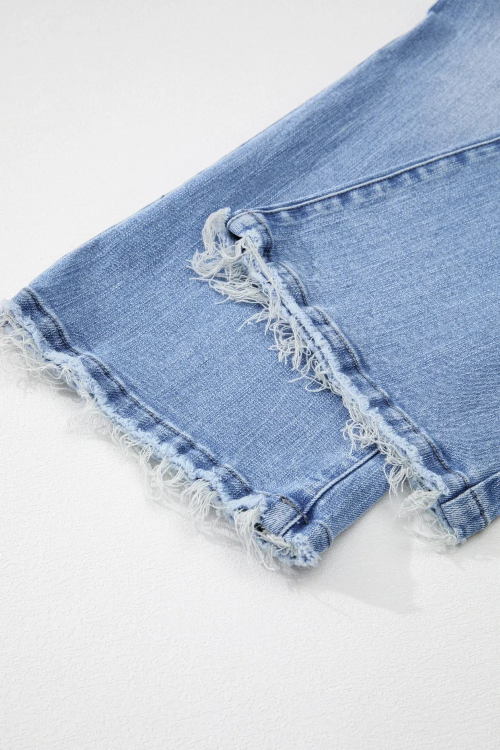 Close-up of light blue denim shorts with frayed edges on a white background