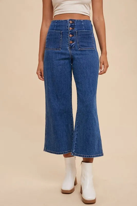 Person wearing blue wide-leg jeans with a beige background