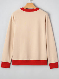 Beige sweater with red trim on a hanger against a gray background