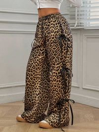 Leopard print pants with black ribbons worn by a person indoors.