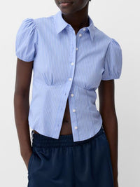 Person wearing a blue puffed-sleeve shirt with a white background