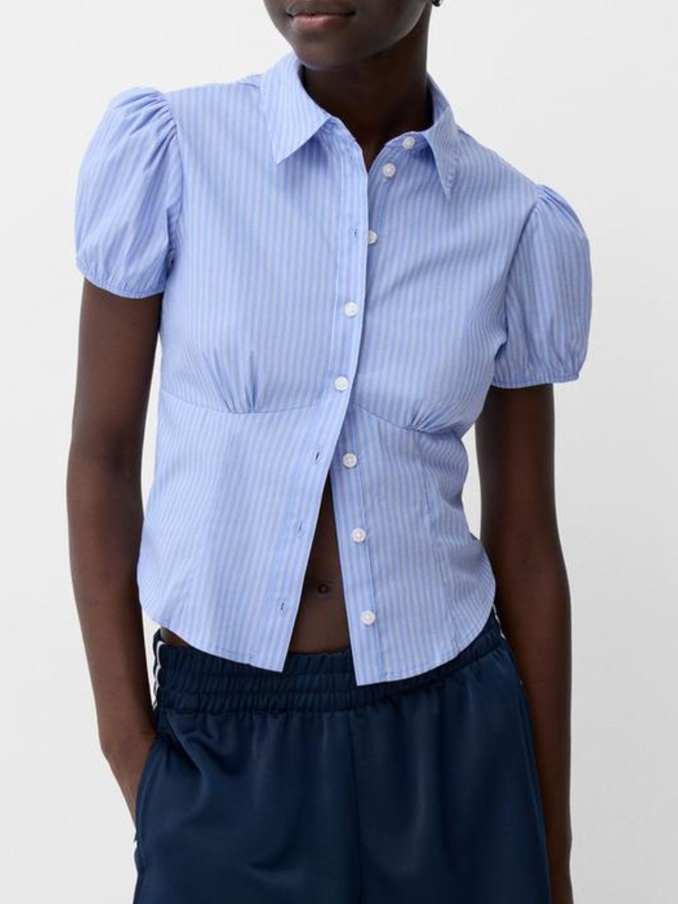 Person wearing a blue puffed-sleeve shirt with a white background