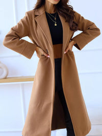 Person wearing a long brown coat with a blurred background