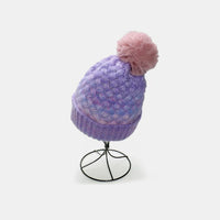 Knitted beanie with a pink pom-pom on a white background