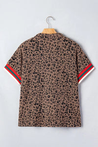 Leopard print shirt with red and green stripes on sleeves, hanging on a wooden hanger against a light gray background.