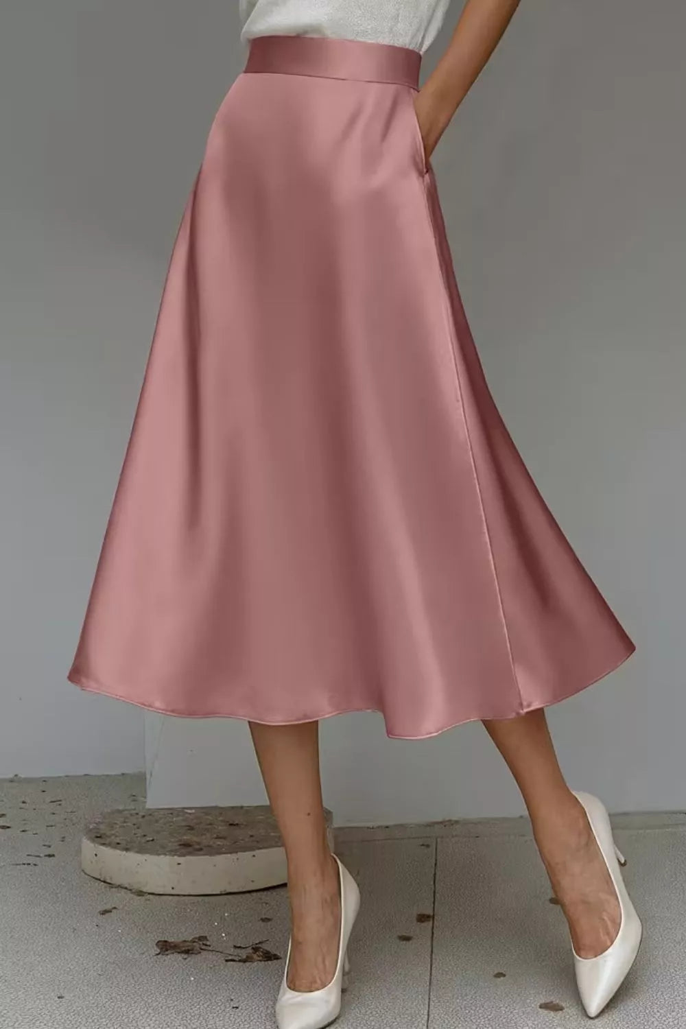 Pink satin skirt worn by a person on a neutral background