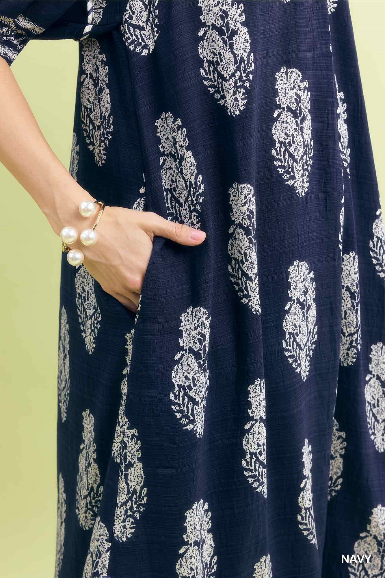 Navy blue fabric with white floral pattern, held by a hand against a light green background.