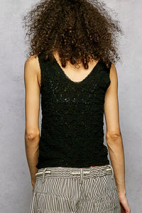 Person wearing a black sleeveless top with a textured pattern against a gray background
