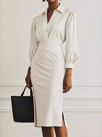 Woman wearing a white dress with long sleeves and a black handbag against a light background