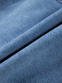 Close-up of blue denim fabric with a visible seam.
