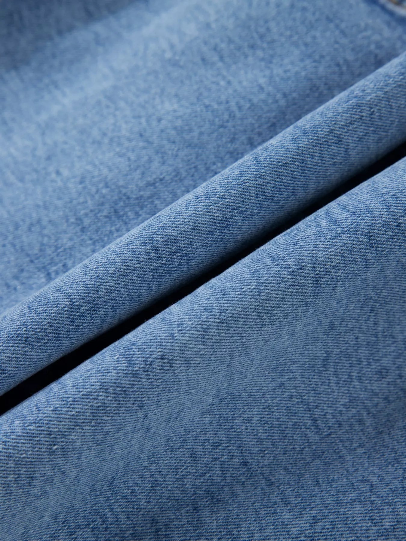 Close-up of blue denim fabric with a visible seam.