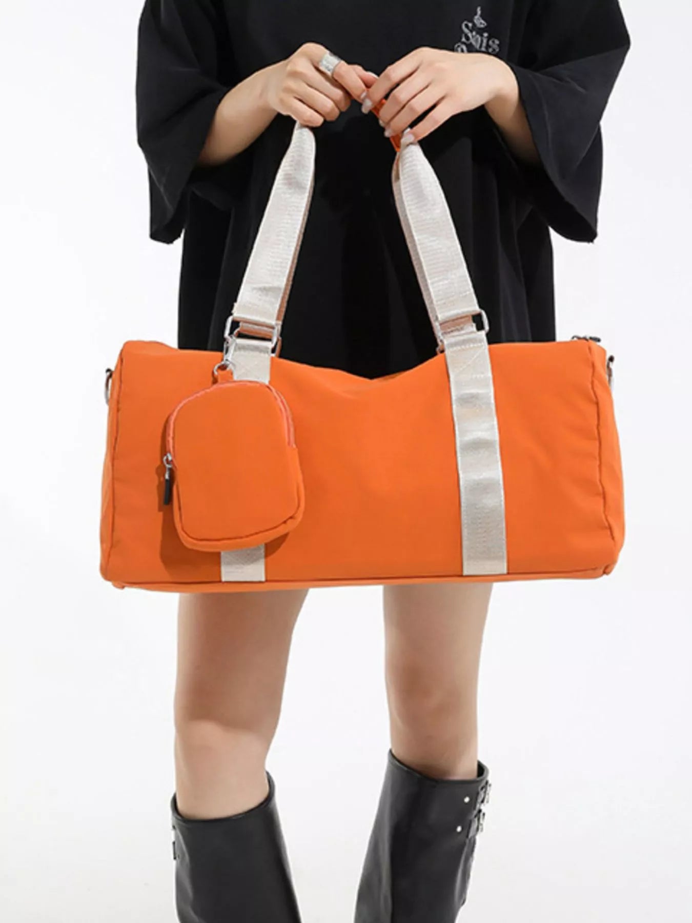 Person holding an orange duffel bag with a white background