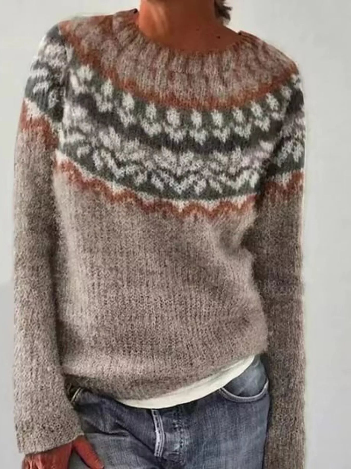 Person wearing a patterned sweater with a neutral background