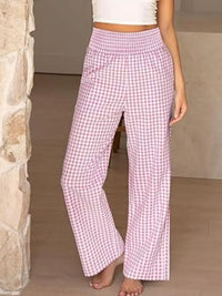 Person wearing pink checkered pants standing against a stone wall.
