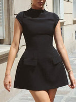 Woman wearing a black dress with a high collar and pockets in an urban setting.