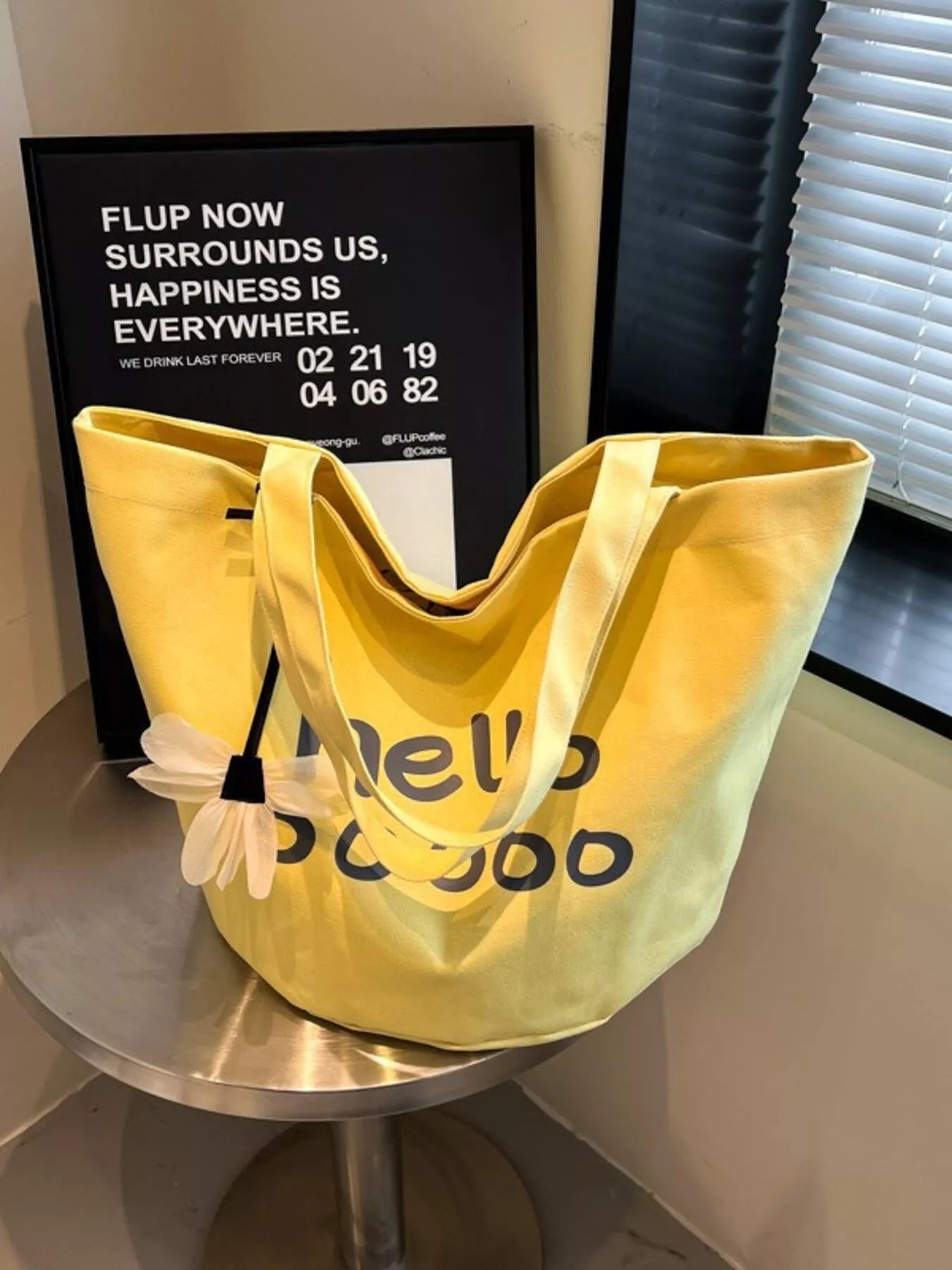 Yellow tote bag with text on a metallic surface